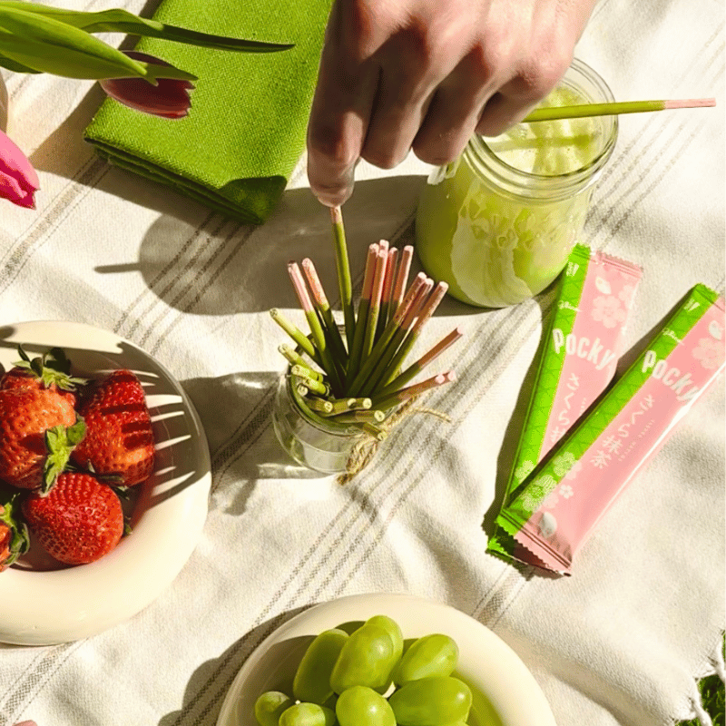 Pocky Double Rich Matcha and Cherry Blossom Matcha on the picnic blanket with fruits and matcha latte